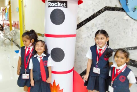 Four-preschool-students-from-Panbai-Flamingo-Kids-standing-beside-paper-model-ISRO-rocket-school-foyer