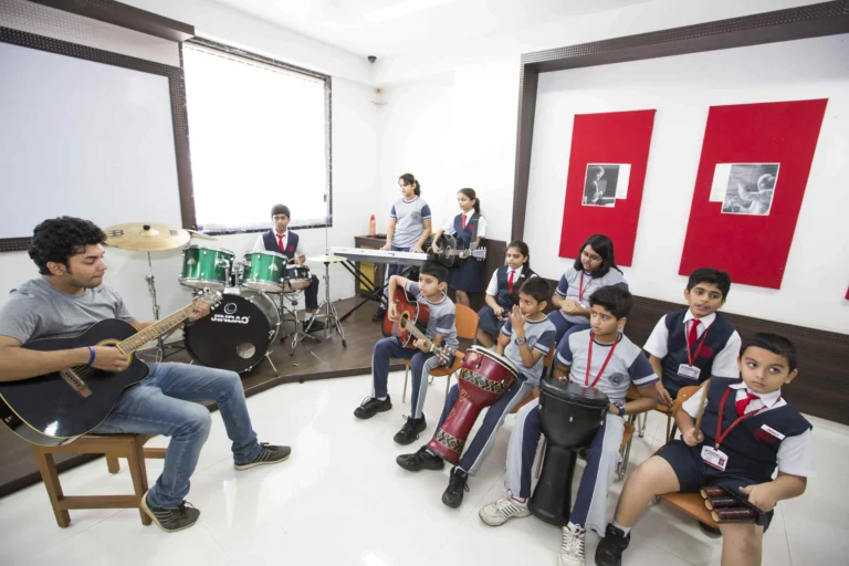 Students at Panbai International School playing various musical instruments with their teacher during a music session.